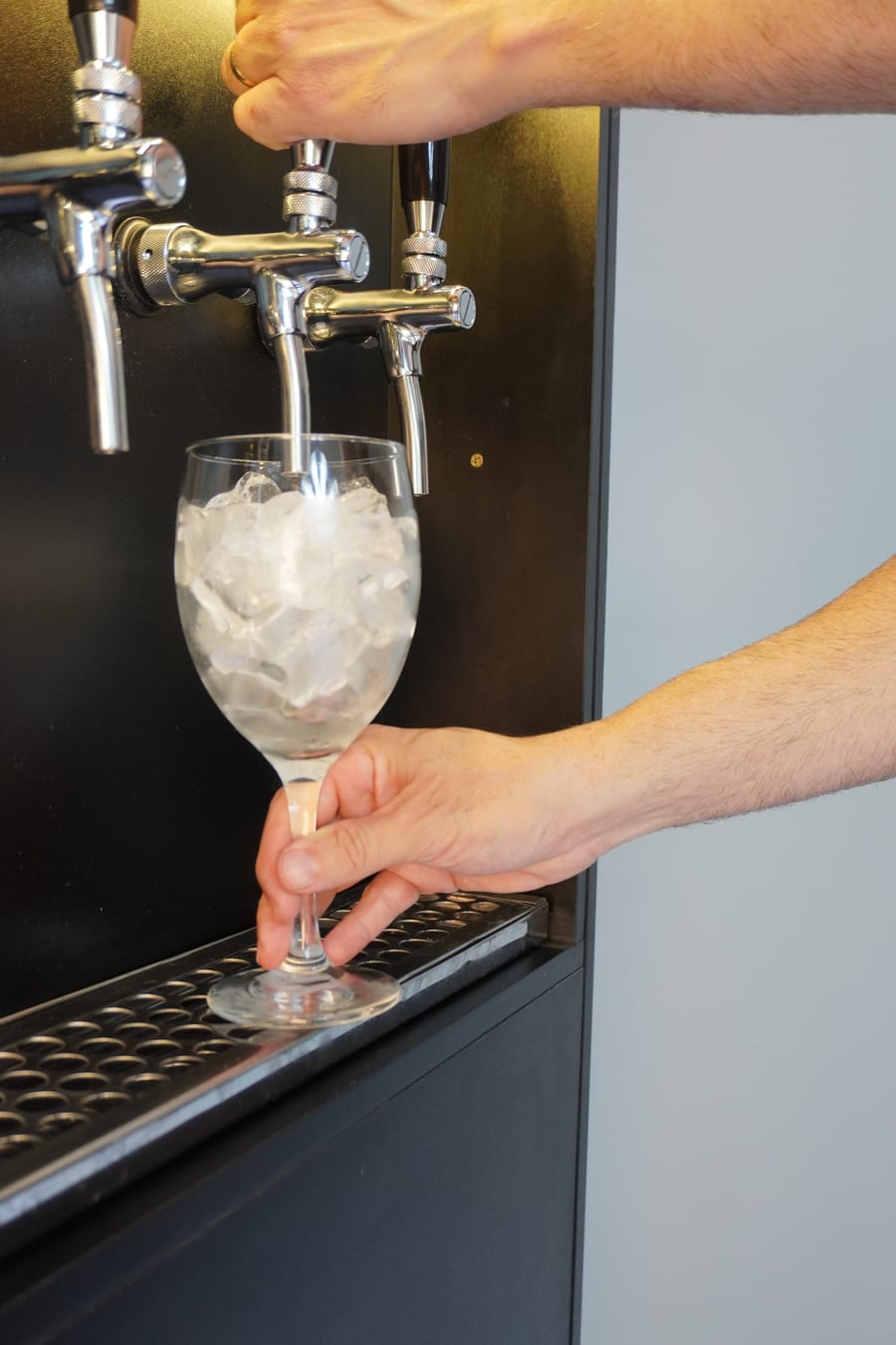 Mão segurando a taça com gelo embaixo da torneira do totem E-Drink