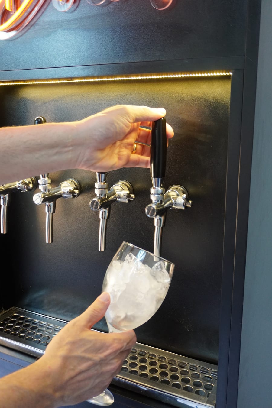Mão abrindo a torneira do totem E-Drink para servir um drink