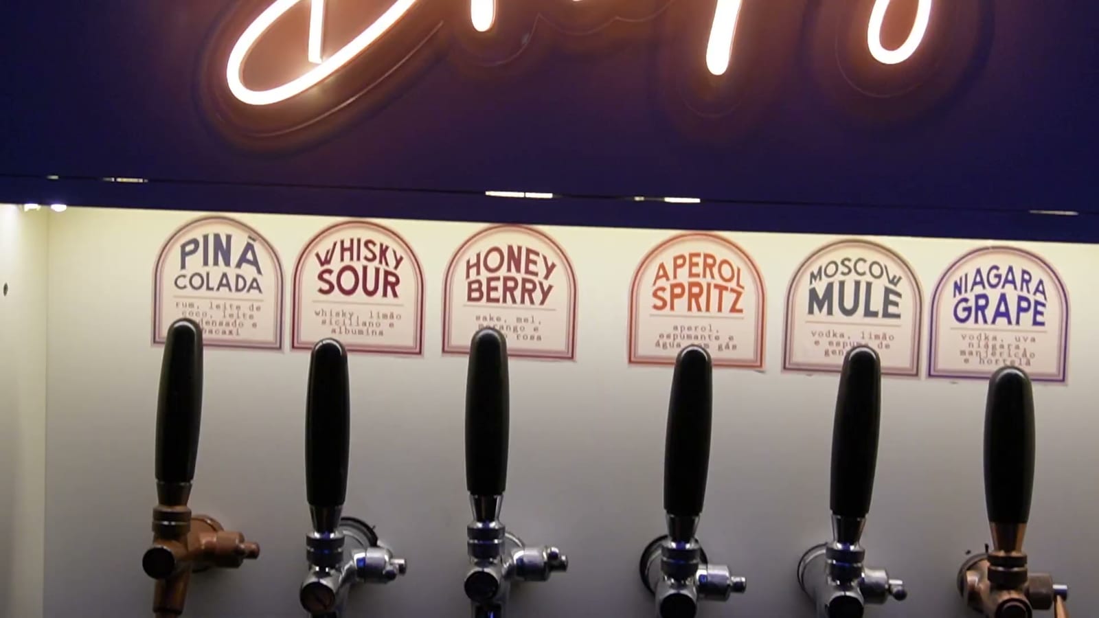 Torneiras do totem E-Drink com os rótulos dos sabores: Piña Colada, Whisky Sour, Aperol Spritz, Moscow Mule e outros
